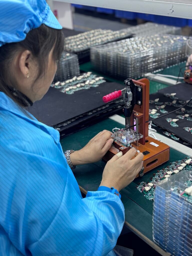 Factory worker performing functional testing on wireless charger PCBA using a custom test fixture