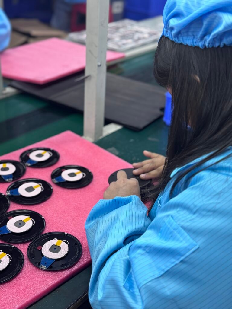 Production line worker carefully assembling the housing casing for circular wireless chargers.